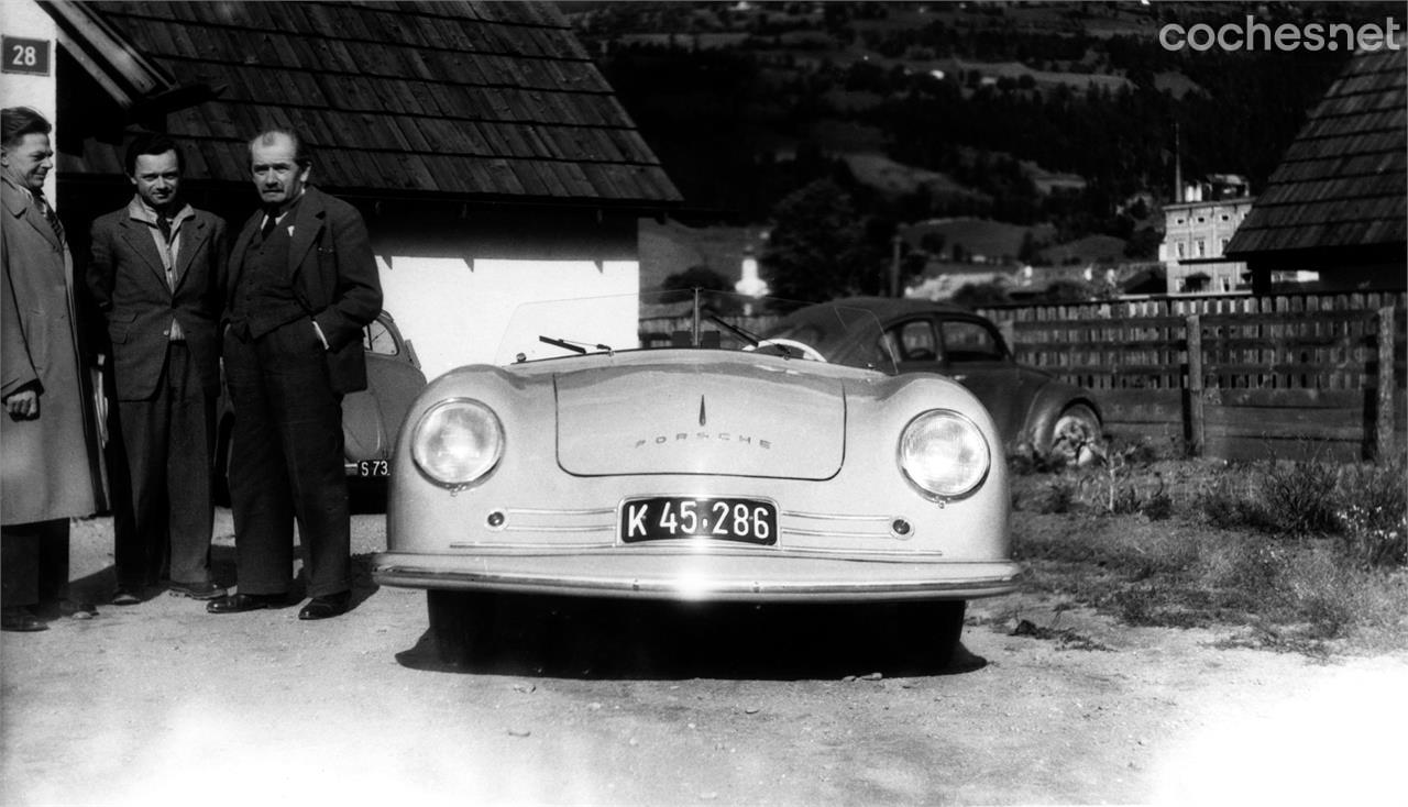 Ferry Porsche (a la izquierda de la imagen) junto a su padre Ferdinand Porsche (manos en los bolsillos) de pie al lado del primer Porsche, el Porsche Nummer 1.